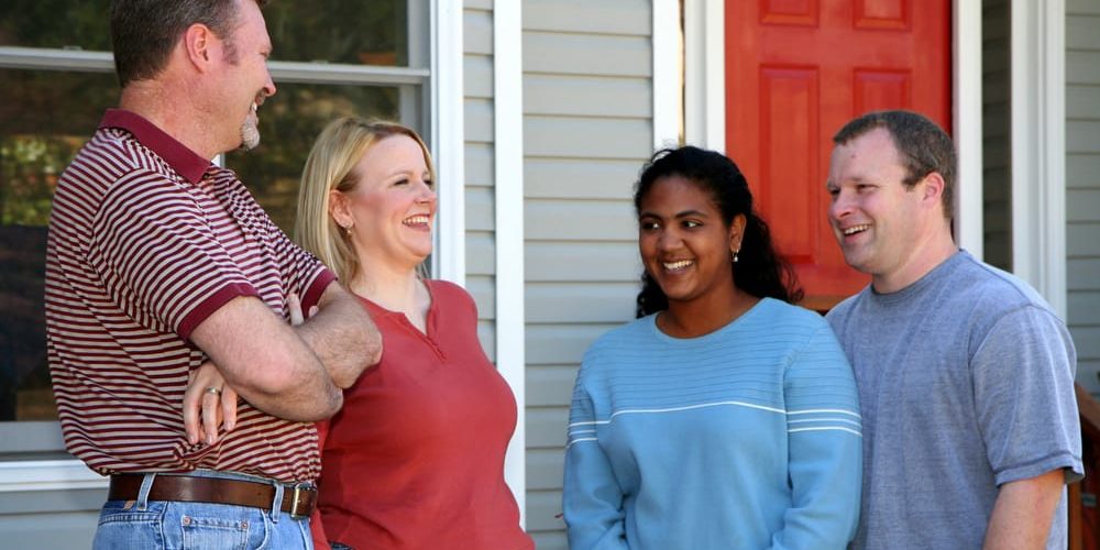 people standing on a porch giving an referring a friend to insurance agent